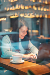 smiling woman working on laptop in restaurant drinking tea eating burger