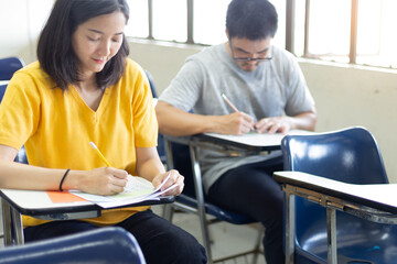 high school,university student study.hands holding pencil writing paper answer sheet.sitting lecture chair taking final exam attending in examination classroom.concept scholarship for education abroad