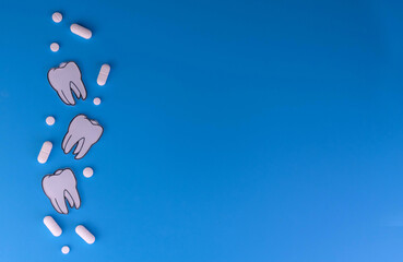 Pills and teeth on a blue background. Toothache concept. Copy space.