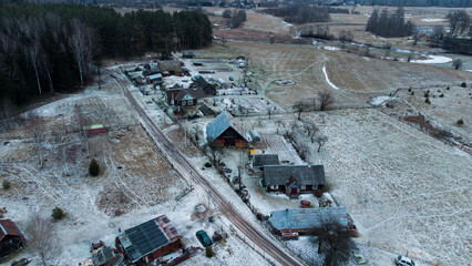 Aerial drone view. Small village around forest and fields.
Winter time.