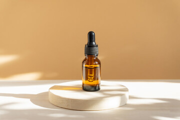 Mock-up of glass bottle, amber color, with a dropper lid, on beige background in rays of sunlight....