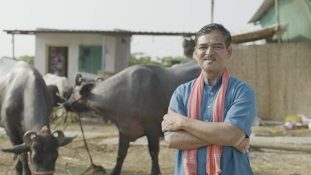 confidently standing happy smiling diary farmer at farm house with crossed arms by looking at camera - concpet of successful dairy farming and small agri-business