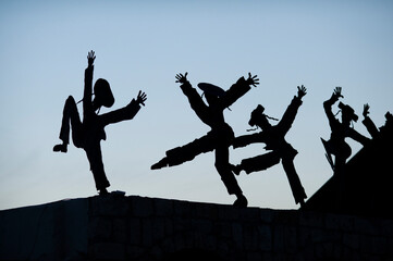 Silhouette metal cutouts of dancing Orthodox Jewish men on a rooftop in northern Israel.