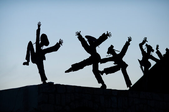 Silhouette metal cutouts of dancing Orthodox Jewish men on a rooftop in northern Israel.