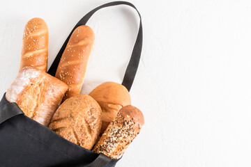 an assortment of baked bread in a black cotton bag on a white background. organic bread concept...