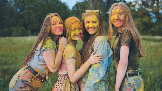 Cheerful girls posing smeared in multi-colored powder.