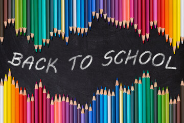 Wave border of colorful wooden pencils on a blank blackboard, back to school concept.