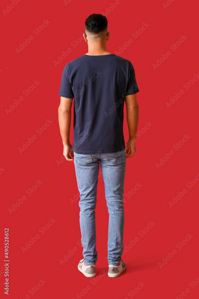 Wall mural Handsome young man in stylish t-shirt on color background, back view