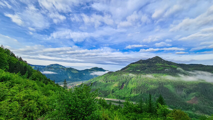 Obraz premium Scenic view from mount Roethelstein near Mixnitz in Styria, Austria. Landscape of green alpine meadow, bushes and high grass in the valley of Grazer Bergland in Styria, Austria. Cloudscape