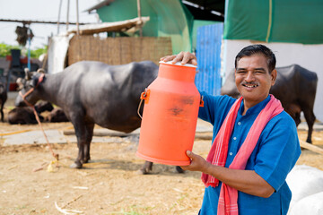 Milk dairy farmer holding milk container by looking at camera - concept of advertisement,...