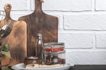 Kitchen utensils and spices on a kitchen countertop against a white brick wall. Food background with utensils with copy space for text. Front view