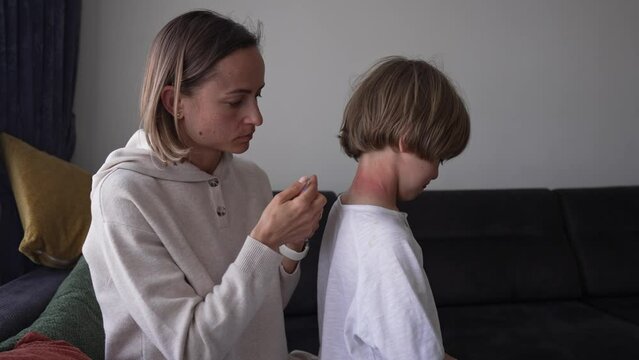 Red pustules and vesicles on the skin of the neck as symptoms of photodermatitis. Allergic reaction to sunlight. Mother rubs the child's neck.