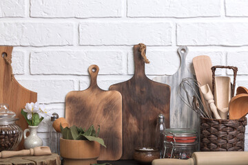 Kitchen utensils and spices on a kitchen countertop against a white brick wall. Food background with wooden eco friendly utensils. Front view