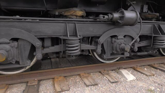 Slow movement of train wheels on rails on old wooden sleepers. The camera moves next to the moving train.
