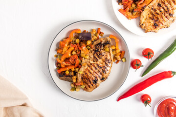 chicken breast and grilled vegetables on a white ceramic plate. top view. white background. a menu of delicious lunches. a copy of the space.