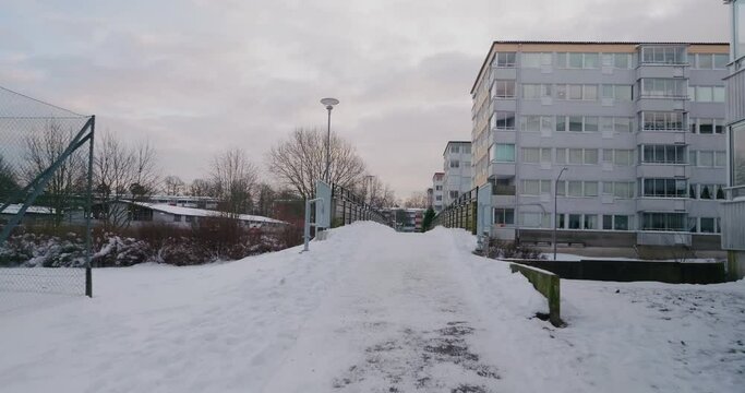 POV Walking Up To a Bridge in an Apartment Building Area in a Snowy Winter, Bor&aring;s, Sweden - Wide Shot tracking Forward