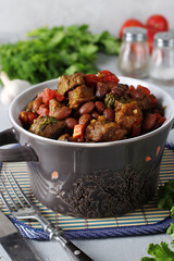 Lobio of stewed beef, red beans, onions, garlic, spices and tomatoes in a ceramic dish on a gray background