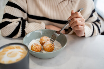 Close-up of the hands of a girl with a fork in her hands,curd syrniki on a plate