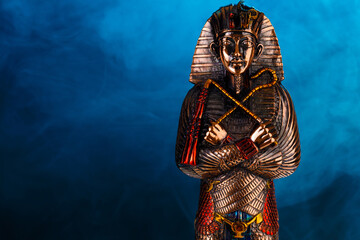 metal pharaoh statue on a blue background with smoke