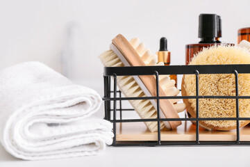 Basket with different bath supplies and towel on table, closeup