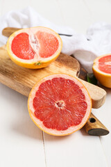 Board with tasty cut grapefruit on wooden background