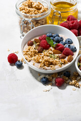 muesli with yogurt and fresh berries for breakfast on white background, vertical