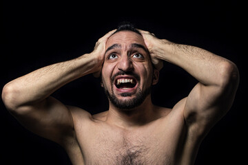 The man clutches his head in madness. Male portrait on a black background. nervous breakdown.