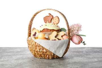 Fototapeta na wymiar Gift basket with cookies, flowers and Easter cake on table against white background
