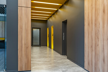 Perspective of a long corridor in office building. Doors of washrooms in hallway. Doors in office...
