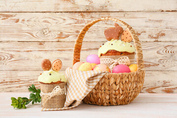 Fototapeta na wymiar Gift basket with painted Easter eggs and cakes on table