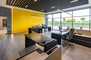 Modern office space with tables and chairs, computers and office supplies with no employees