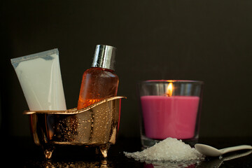 Body care products, shower gel, body cream, candles and salt for baths on black background