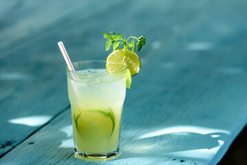 Caipirinha drink with lime on a blue wooden table. Typical Brazilian drink made with cachaça, lemon, ice and sugar.