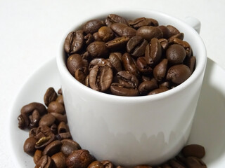 White cup of coffee (taza de café) full of fresh roasted coffee beans (granos de café) ready to be prepared. 
