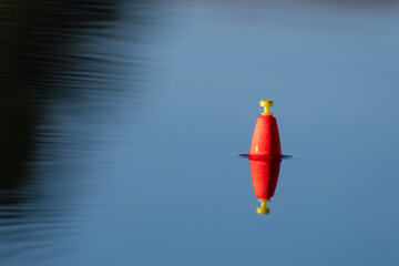 A fisherman's bobber or float in the water. Time to relax. Plenty of copy space.