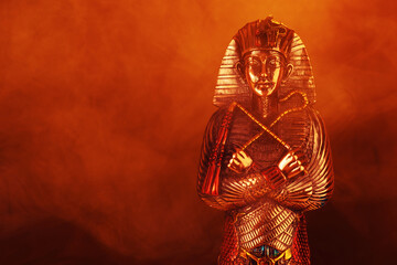 egyptian golden pharaoh statue in red mist on black background