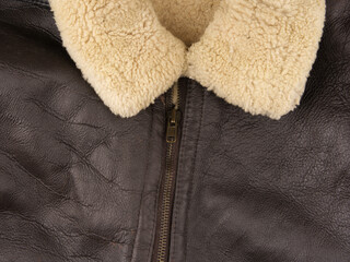 Part of a warm mens jacket on a gray background. The zipper is fastened and the lined collar is visible. Close