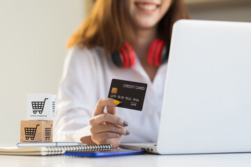 Woman showing credit card while using laptop. Concept of financial transactions and online shopping.