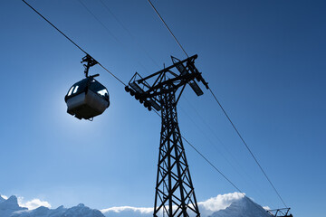 Low angle view of a silhouette of a ropeway with passengers inside, hanging high on cable is moving...