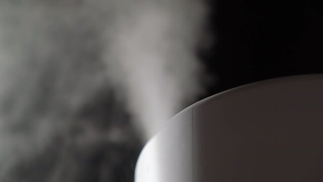 Household humidifier. White electronic device for humidification, ionization and air purification. White water vapor. Steam on a black isolated background