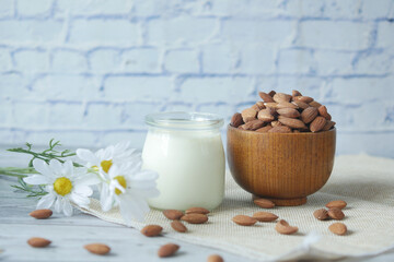  glass of milk and almond nuts in a bowl on table 