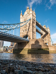 Fototapeta na wymiar Tower Bridge, London. A low, wide angle view of the popular landmark crossing the River Thames at low tide.