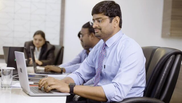 Young smiling corporate employee working with showing thumbs up by looking at camera during conference meeting - concept of successful career, employment and professional occupation