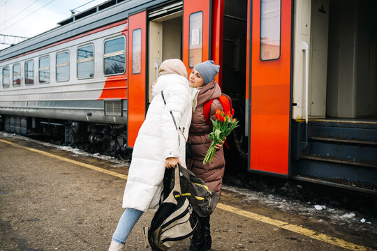 girls say goodbye hugging on the station platform