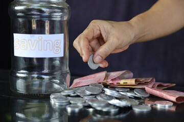 young man holding a coin putting it in a glass. the concept of saving money for financial accounting
