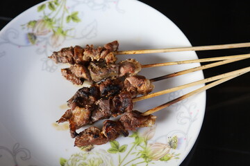 Grilled chicken satay skewers with peanut butter sauce.