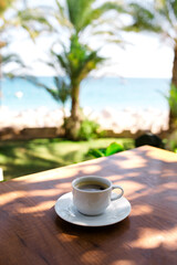 Coffee cup on a wood table over blue sky and sea background. Summer fun, enjoying life, vacations, holidays, tourism, travel concept