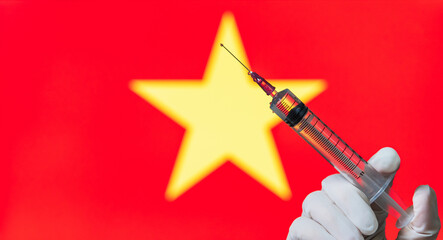 Vaccination is a common practice in Vietnam. On the background of a country flag, a vaccine to...