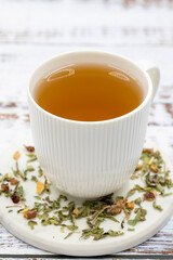 Relax herbal tea on a wooden background. Herbal tea prepared with lemon balm leaves, jasmine flower, apple peel, orange, lemon and hibiscus particles.
