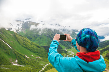 Woman hiker taking photo on the top of mountain